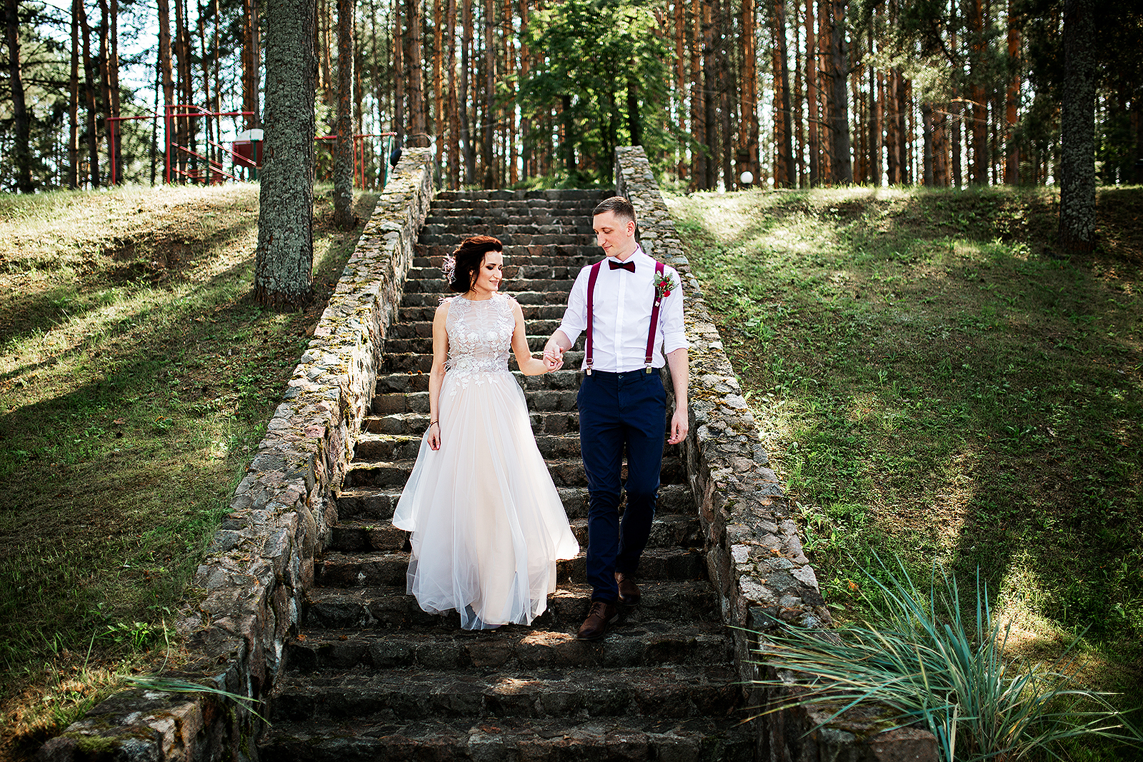 bride and groom are going down the stairs in the forest