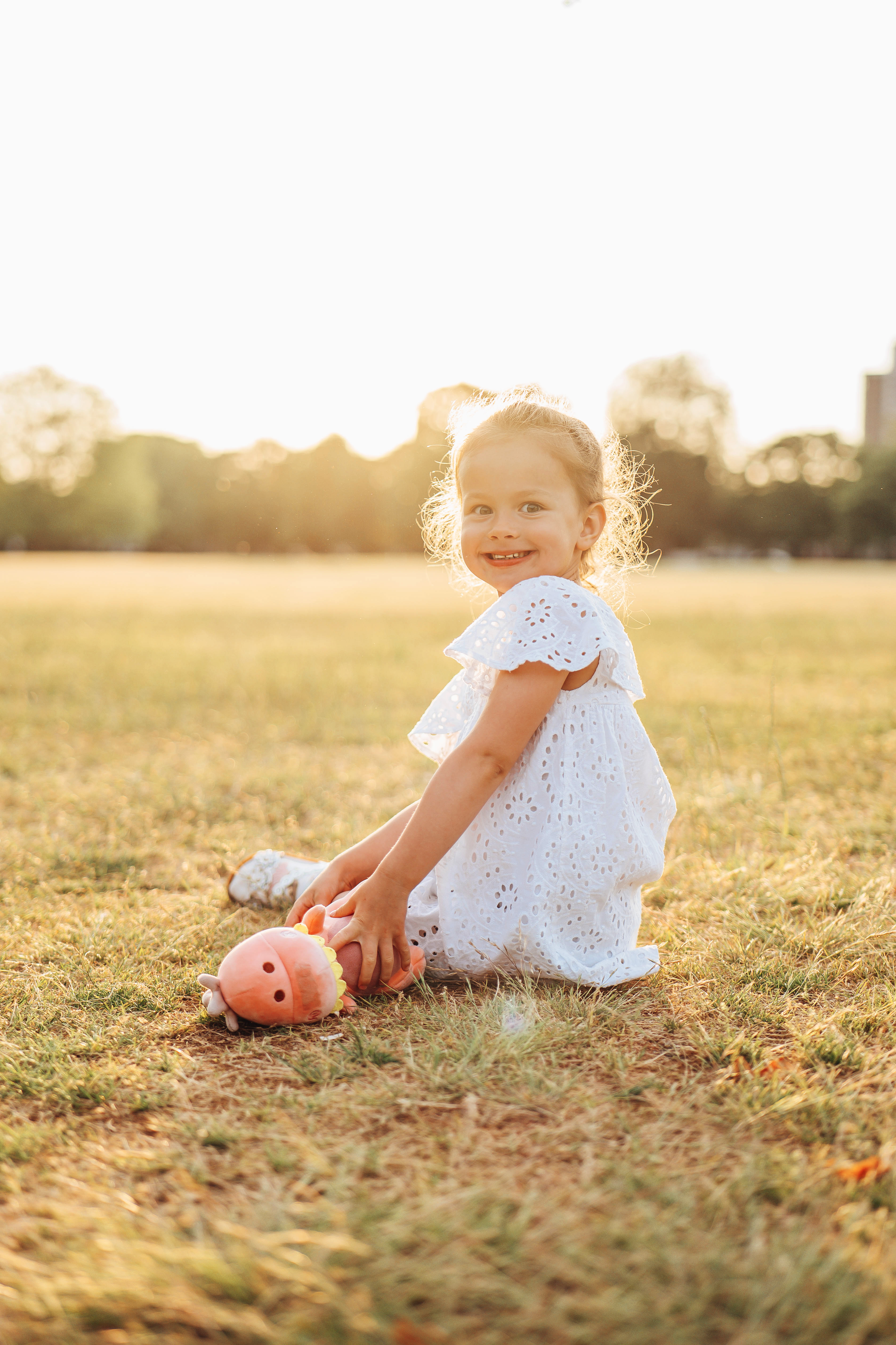 Small girl in the grass smiling, sunset